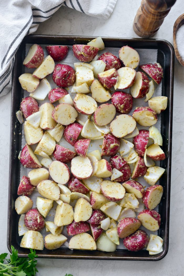 spread onions and potatoes onto parchment paper lined sheet pan