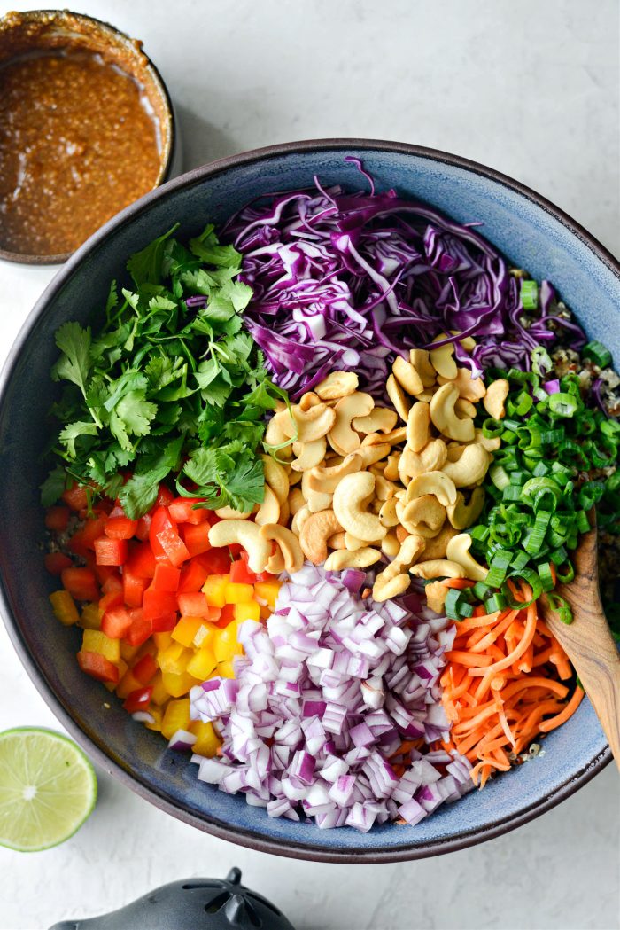 cabbage, cilantro, peppers, onion carrot, cashews and green onion in bowl with quinoa