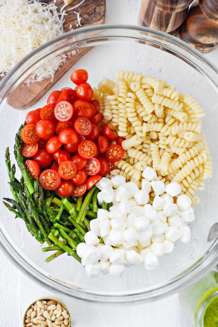 cooked pasta, cherry tomatoes, asparagus and mozzarella in bowl.