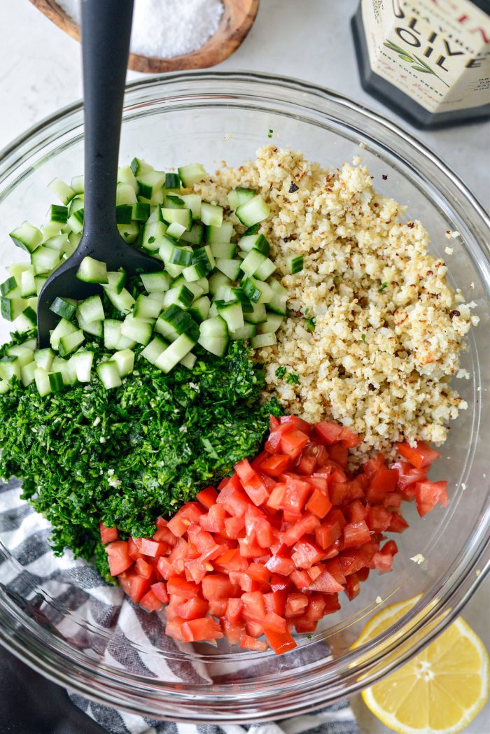 roasted cauliflower rice, parsley mixture, diced tomato and cucumber in bowl.