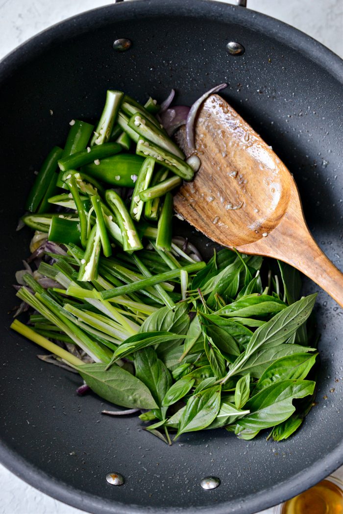 adding serrano, julienned green onion, thai basil to pan