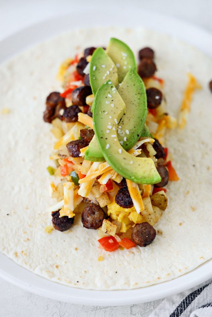 eggs, cheese, sausage, pepper and onions and avocado on a tortilla