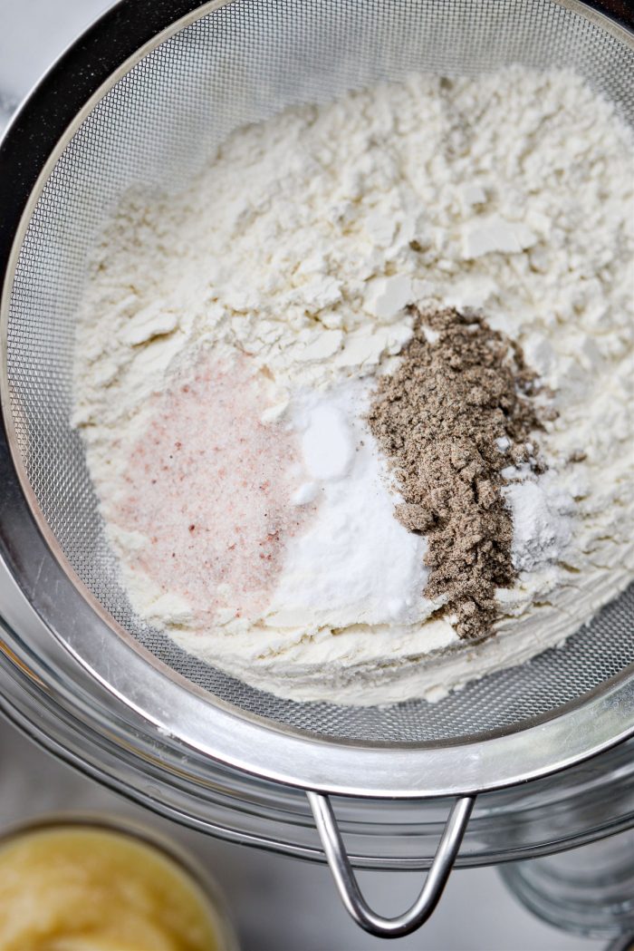 flour, baking soda, baking powder and cardamom in a mesh sieve