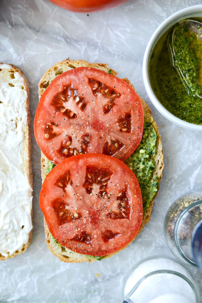 top pesto with sliced tomato, salt and pepper