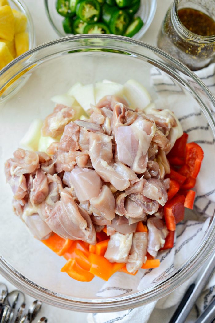 peppers, onions and cubed chicken thighs in bowl