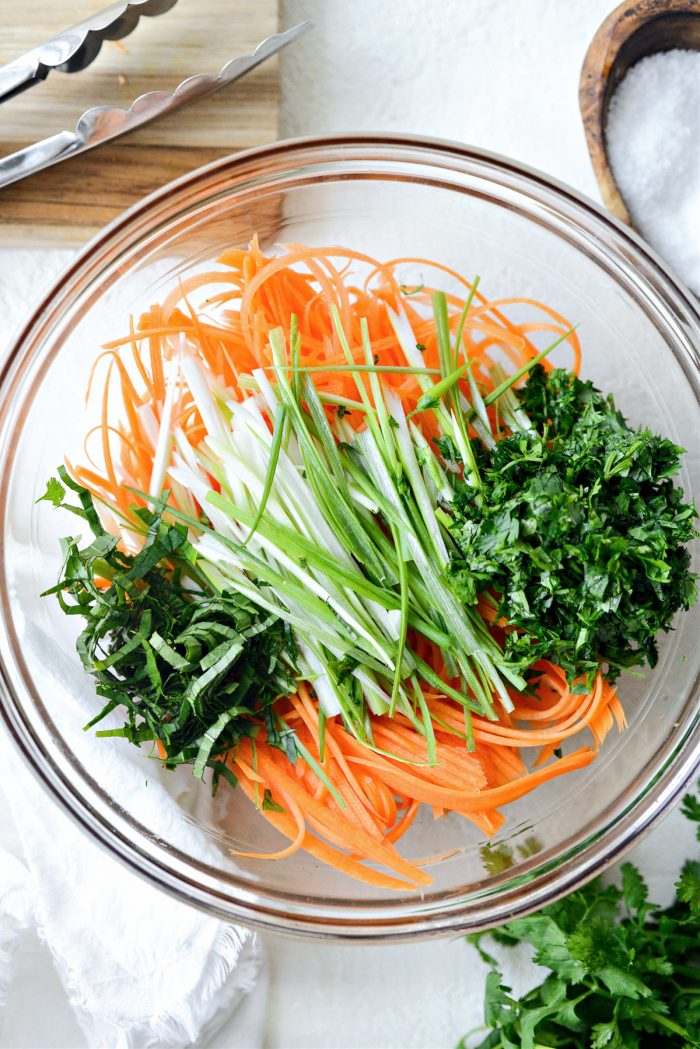 carrots, green onion, thai basil and cilantro in a bowl.