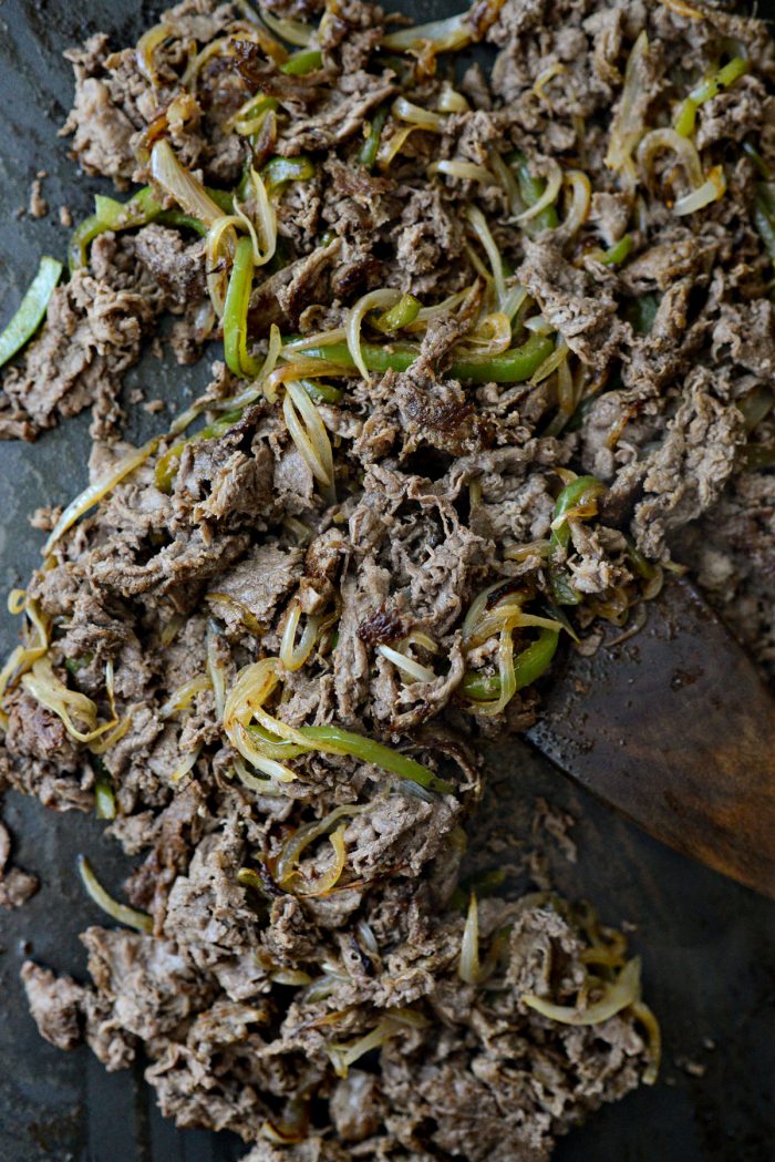 tossing peppers and onions with cooked shaved steak