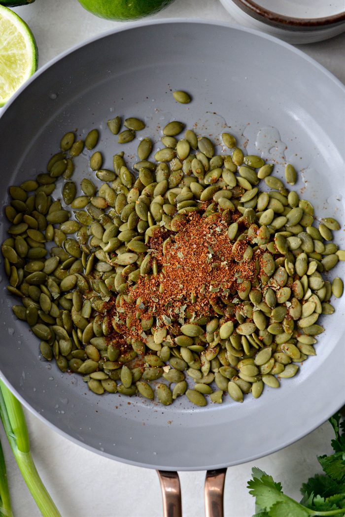 pepitas, lime juice and Mexicali seasoning in pan