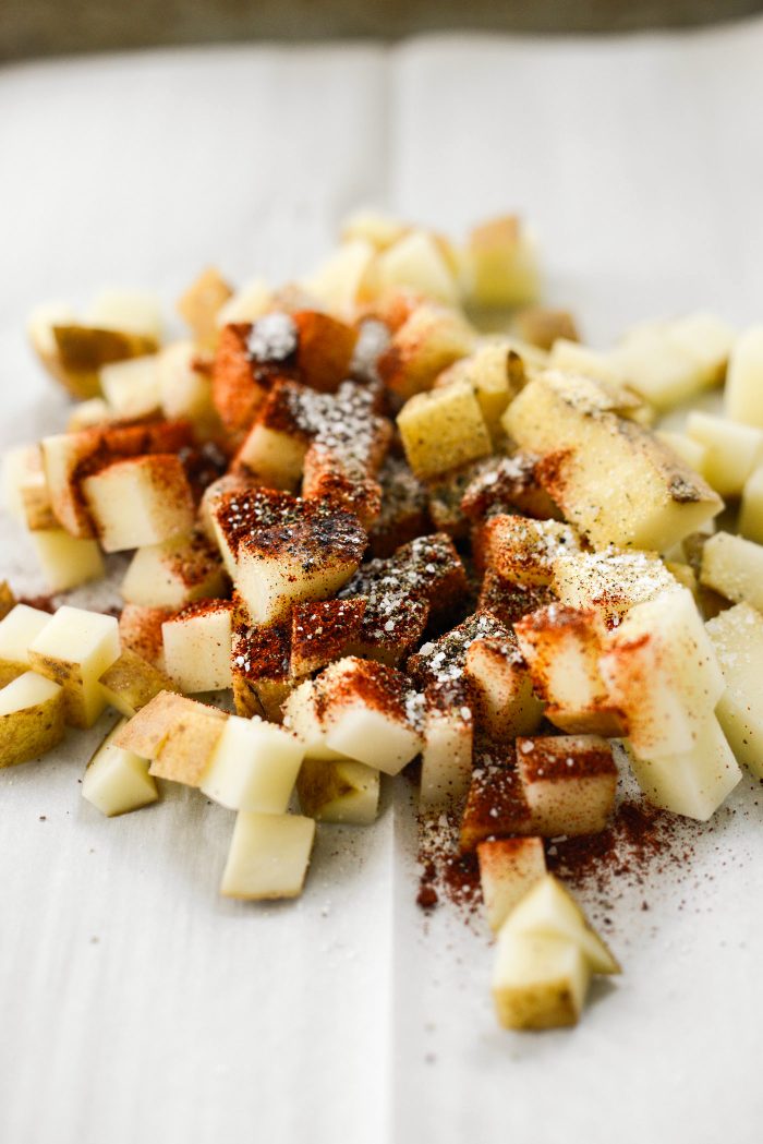 diced potatoes, oil and spices on a sheet pan