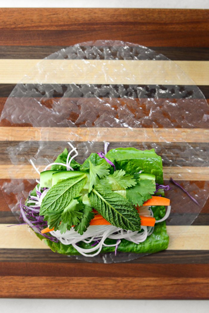 place rice paper on clean surface and top with romaine, noodles, veggies and herbs