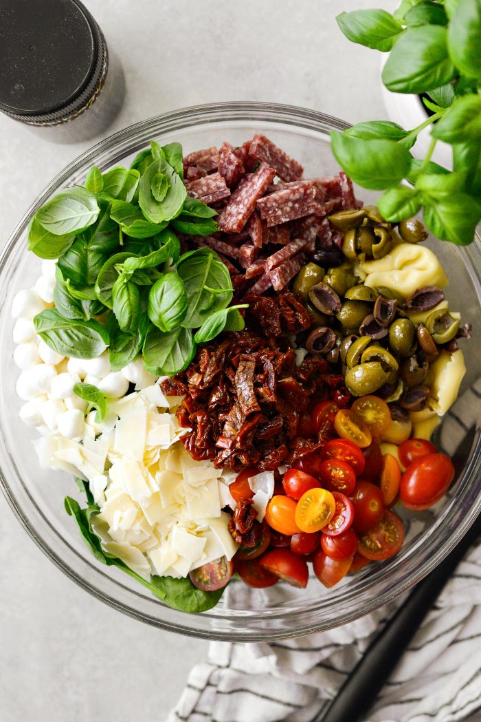 add salami, olives, tomatoes, sun-dried tomatoes, tuscan cheese blend, mozzarella and basil
