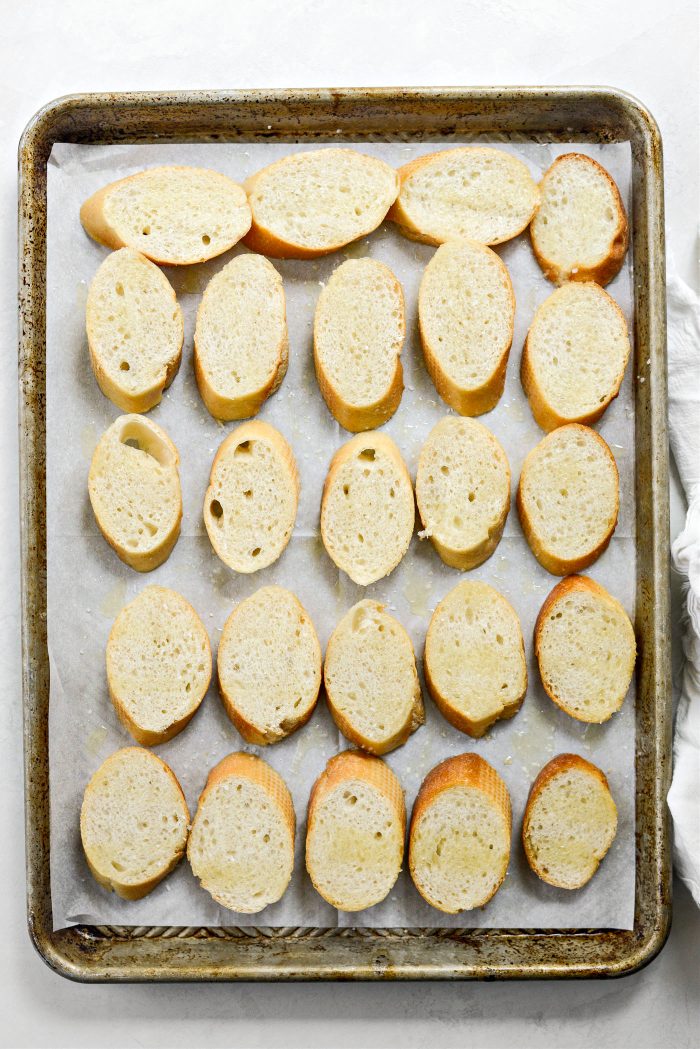 sliced baguette on rimmed baking sheet