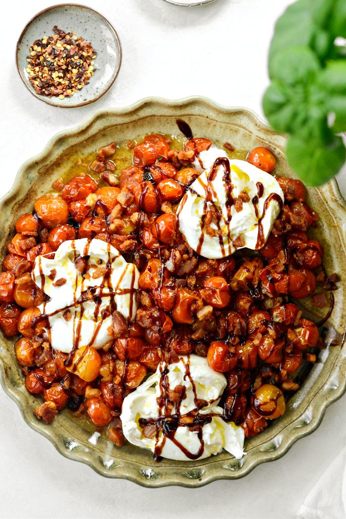 add tomatoes, burrata and pancetta to a platter. drizzle with olive oil and balsamic