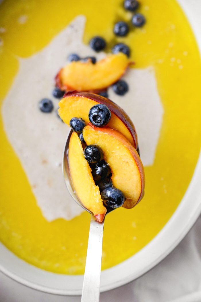 spoon peaches and blueberries and some of the liquids over top of the batter
