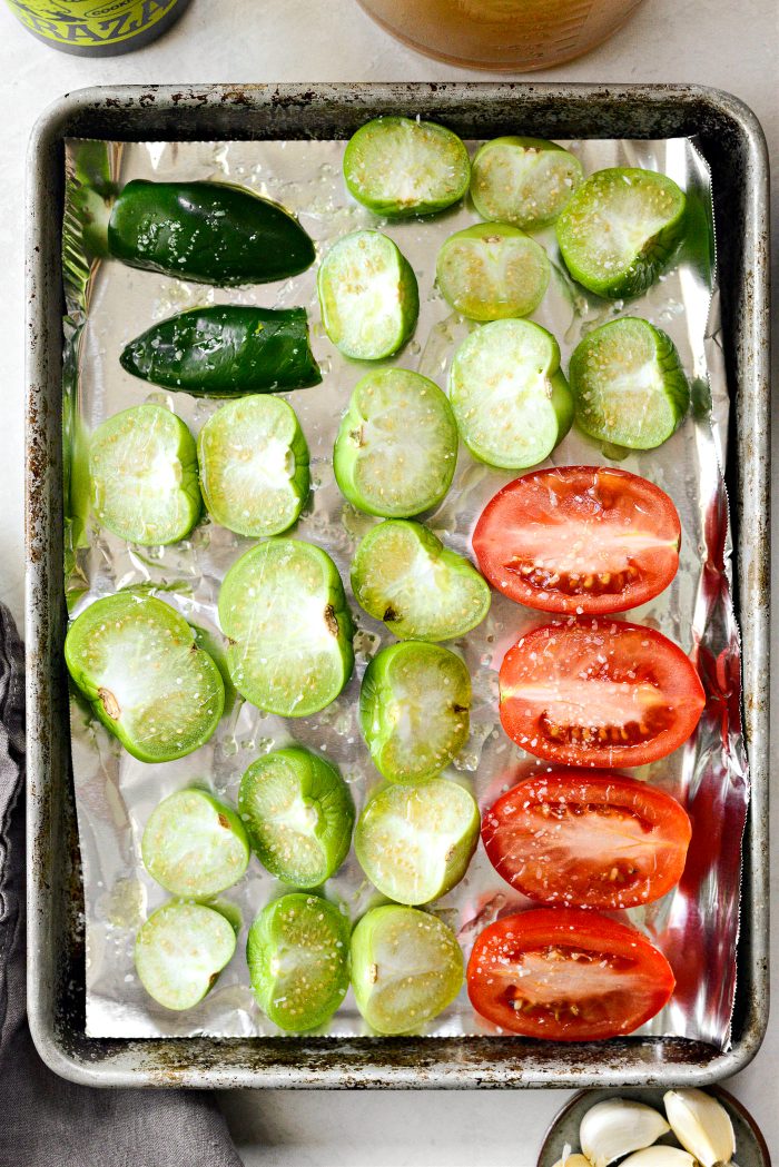 tomatillos, roma tomatoes and jalapeño on roasting pan with oil and salt