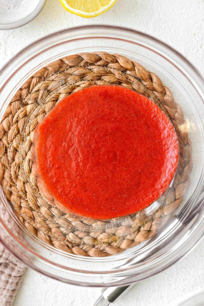 strain strawberry puree into a bowl